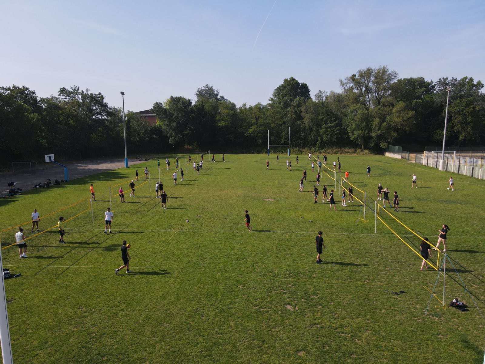 Vue aérienne d'un tournoi de volley en extérieur organisé par le club : plusieurs terrains installés sur herbe sous le soleil
